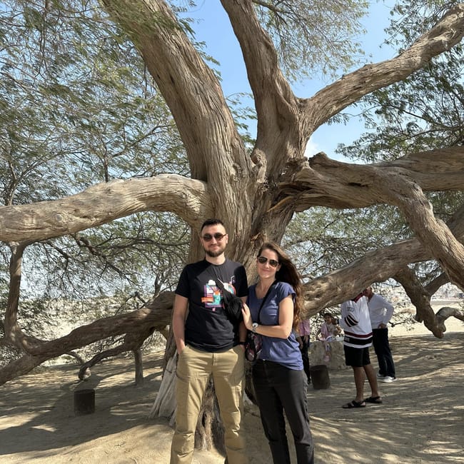Tree of life w bahrajnie, z parą stojącą pod rozłożystym drzewem na pustynnym tle