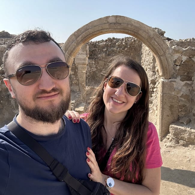 Para przy ruinach bahrain fort, stojąca pod kamiennym łukiem w słońcu