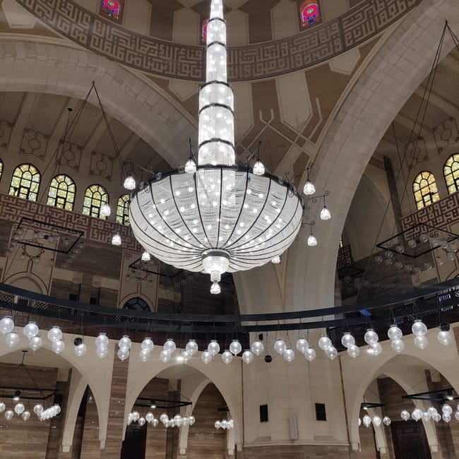 Wnętrze meczetu al fateh grand mosque w bahrajnie z ogromnym żyrandolem i łukami.