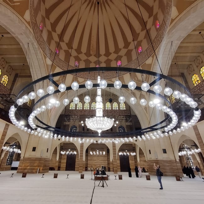 Wnętrze meczetu al fateh grand mosque w bahrajnie z ogromnym żyrandolem i sklepieniem kopuły