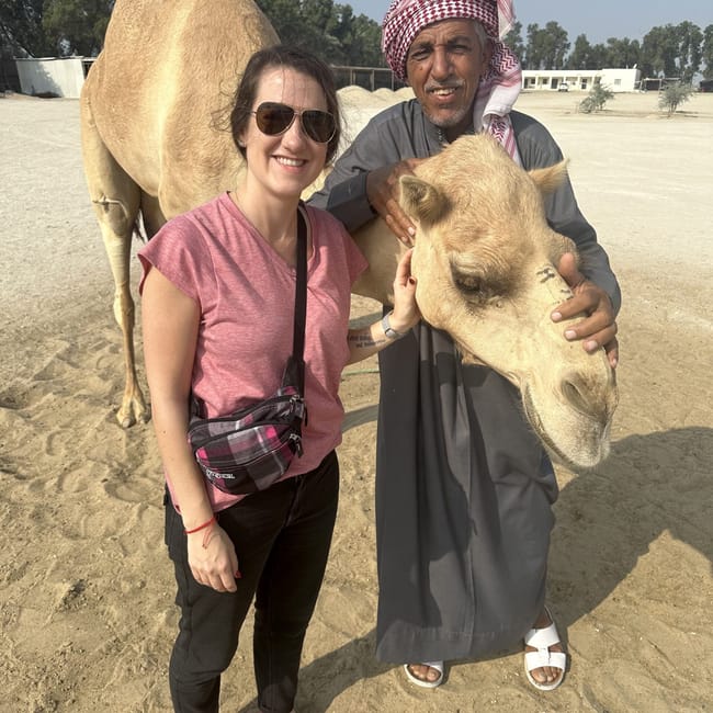 Camel farm zallaq w bahrajnie: kobieta i mężczyzna pozują z wielbłądem.