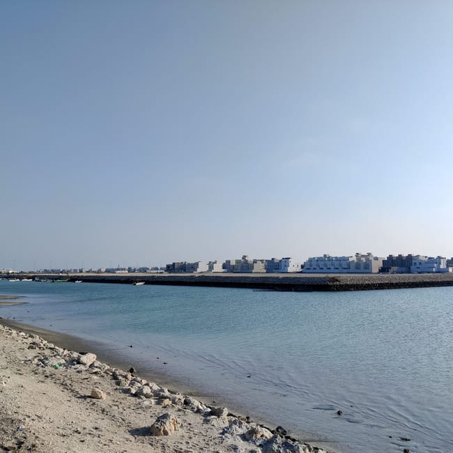 Wybrzeże w diyar al muharraq w bahrajnie z spokojną zatoką i zabudową na horyzoncie