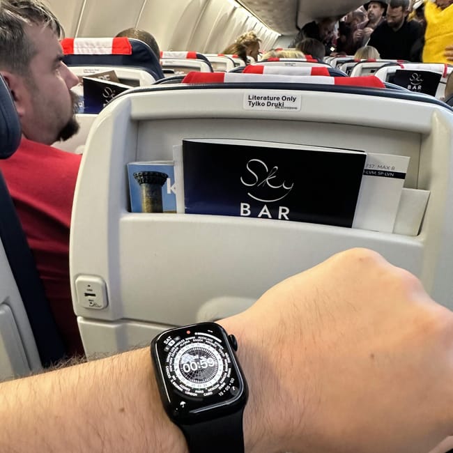 Inside an airplane to cairo, a passenger checks a smartwatch while seated in economy class.