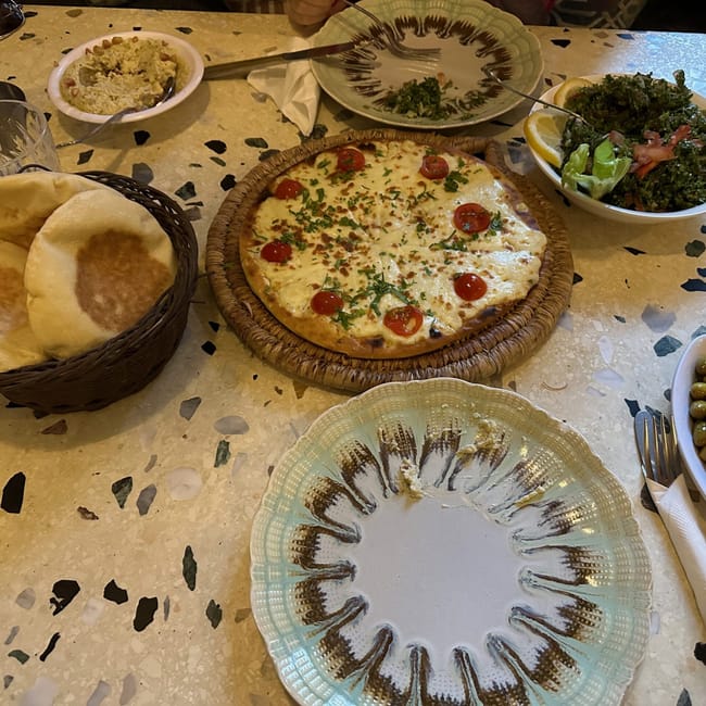 Egyptian table with flatbreads, a cheese pizza, salads, and olives