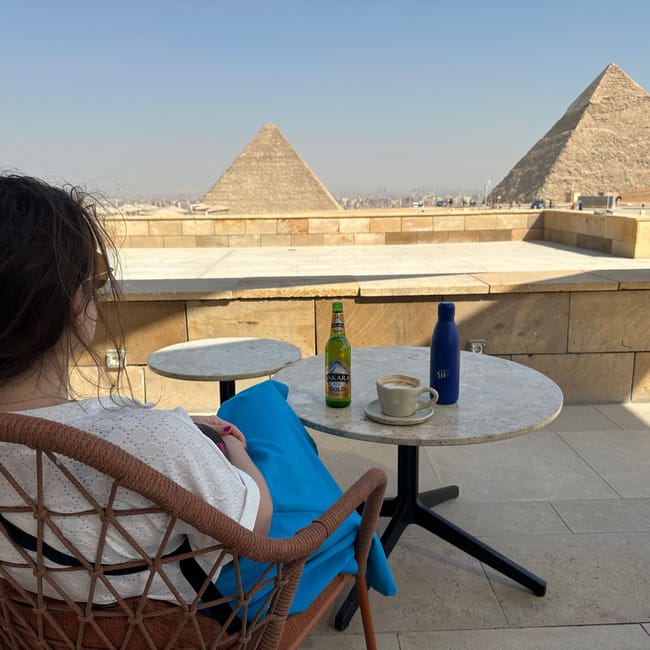 Woman seated at a cafe overlooking the pyramids of giza in egypt
