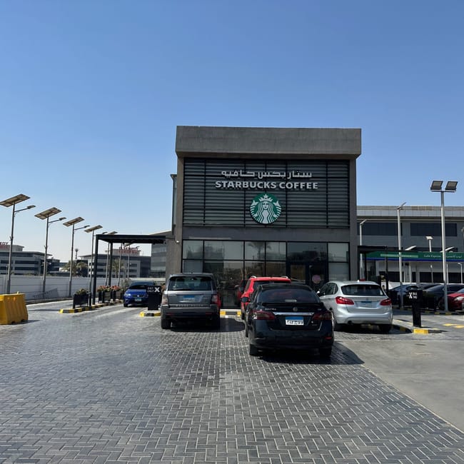 Starbucks coffee storefront in egypt with parked cars under a clear blue sky