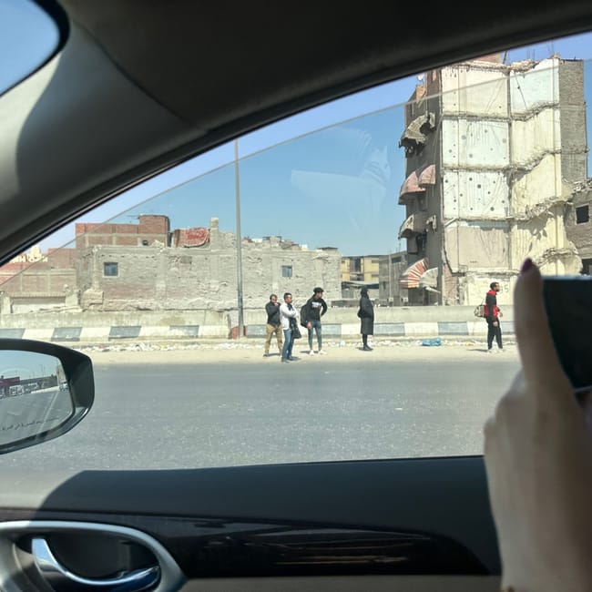 View from a car of damaged apartment buildings and pedestrians in safety, egypt