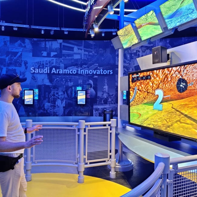 Wystawa saudi aramco innovators w ithra w dammam, z interaktywnym ekranem i odwiedzającym.