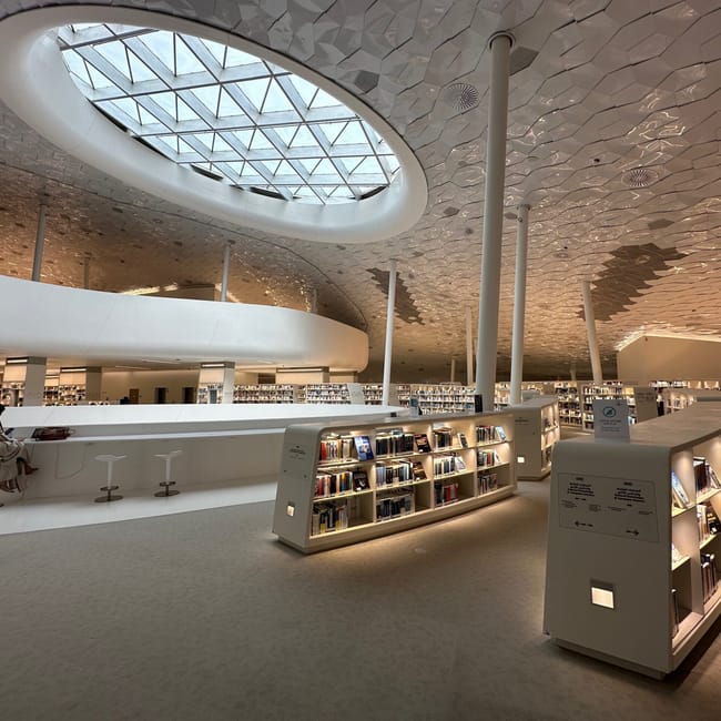 Wnętrze biblioteki ithra w dammam, arabia saudyjska, z półkami z książkami i owalnym świetlikiem w suficie