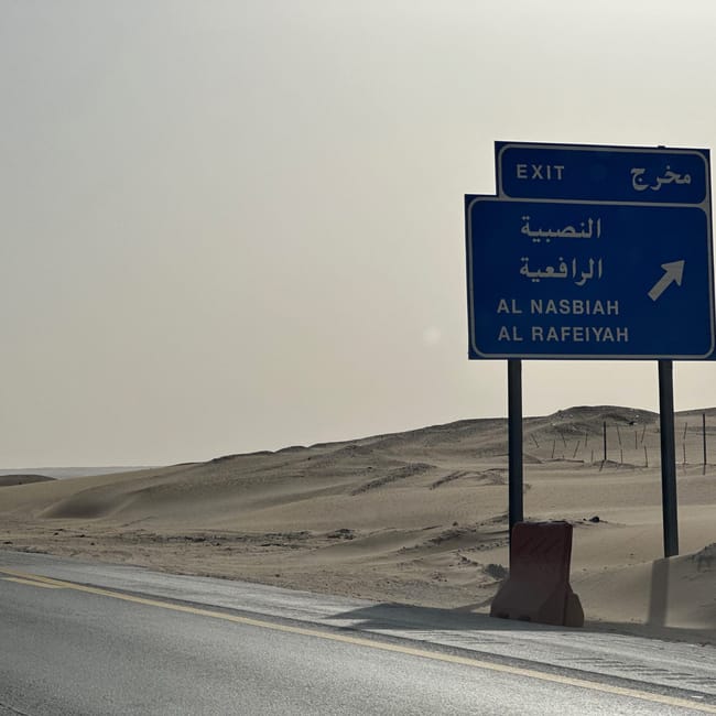 Pustynna droga w arabii saudyjskiej z niebieskim znakiem zjazdu do al nasbiah i al rafeiyah.