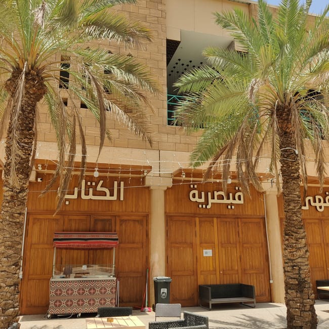 Riyadh deera square z palmami, tarasowymi stolikami i arabskimi szyldami na budynku