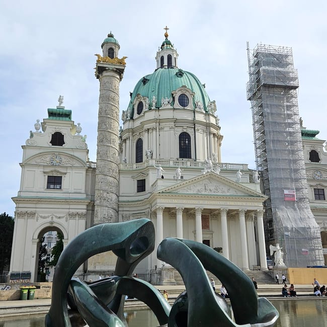 Kościół św. Karola w wiedniu z zieloną kopułą i nowoczesną rzeźbą przed fasadą