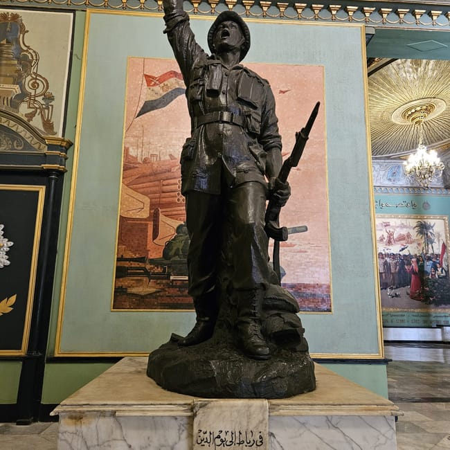 Pomnik żołnierza w cairo national military museum w kairze, z uniesioną ręką i karabinem.