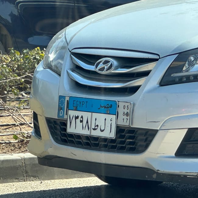 Przód samochodu z egipską tablicą rejestracyjną na ulicy.