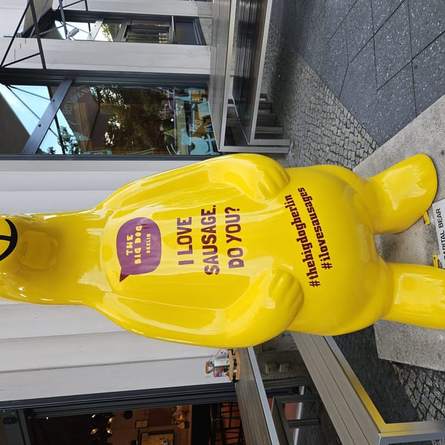 Żółta rzeźba niedźwiedzia przed restauracją w berlinie z napisem i love sausage, do you?