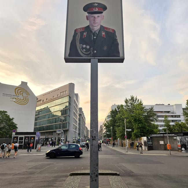 Checkpoint charlie w berlinie z dużym zdjęciem żołnierza na słupie i ulicą w tle