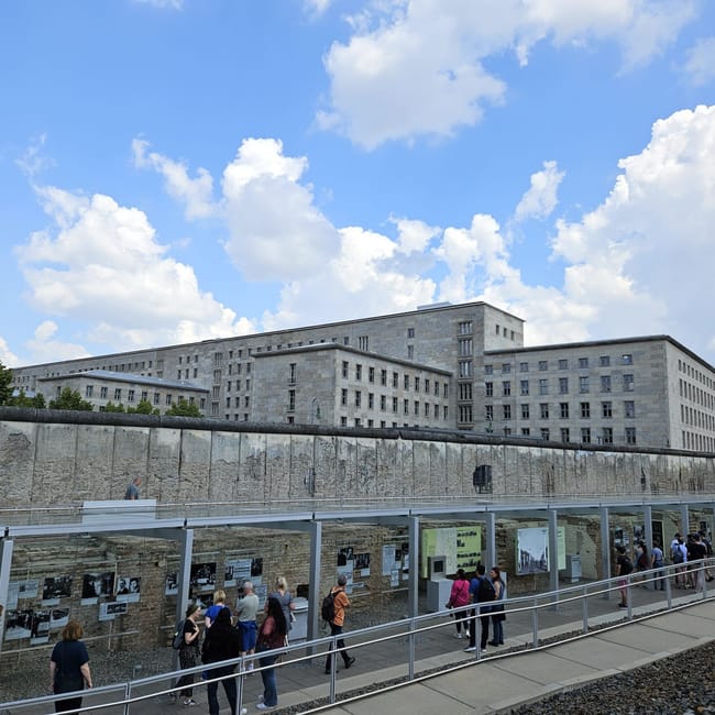 Berlin terror museum w berlinie z fragmentem muru berlińskiego i zwiedzającymi.