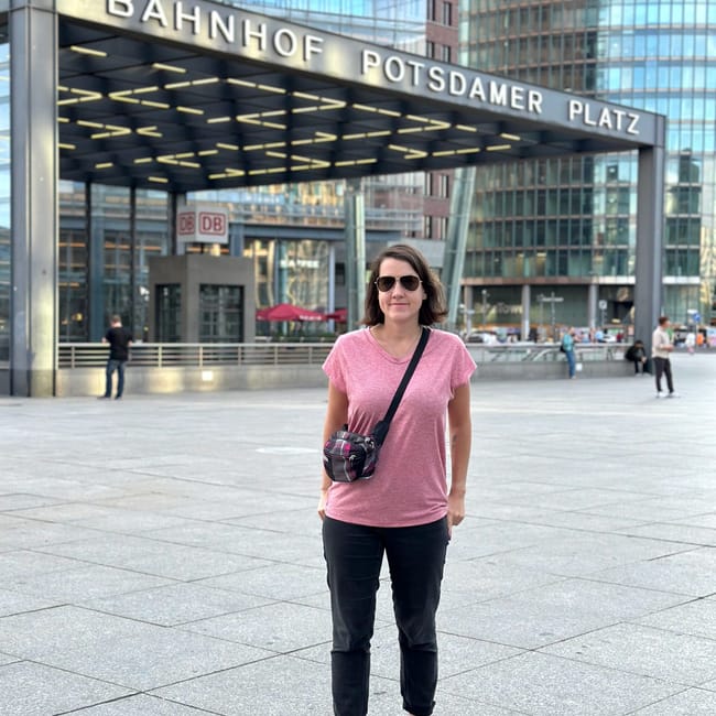 Kobieta stoi przed wejściem do bahnhof potsdamer platz w berlinie.