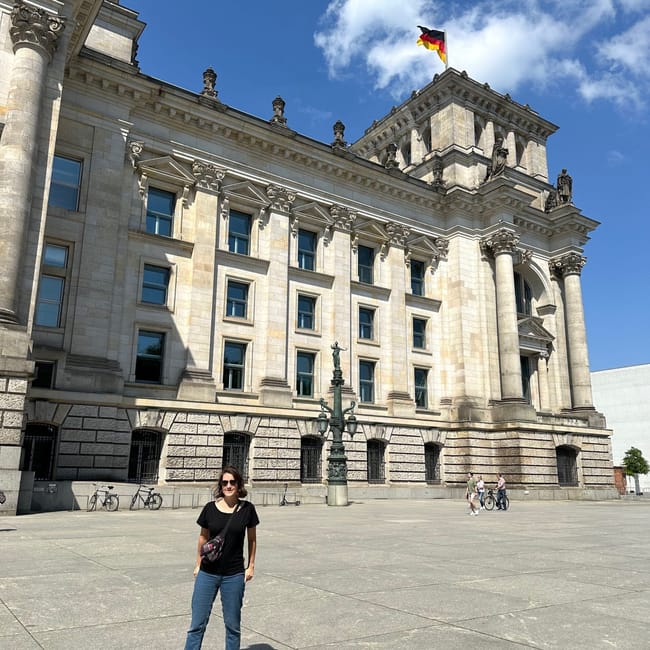 Budynek reichstagu w berlinie z niemiecką flagą na dachu i osobą stojącą przed фасadą