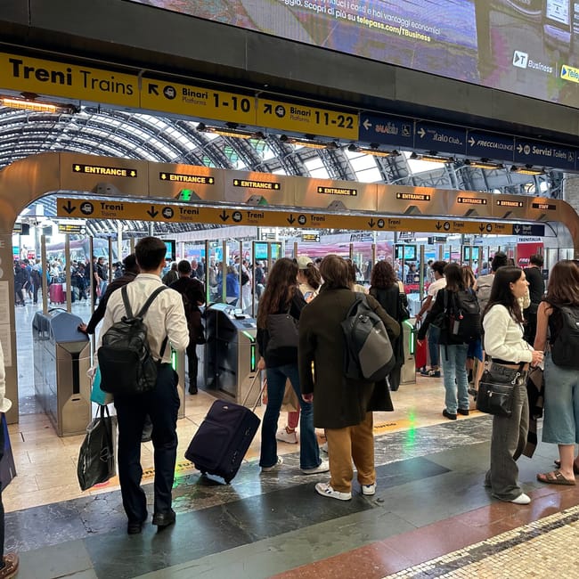 Wejście na perony kolei w mediolanie z kolejką podróżnych i oznaczeniami treni.