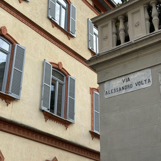 Kamienica przy via alessandro volta w como z jasnymi okiennicami i ozdobną fasadą