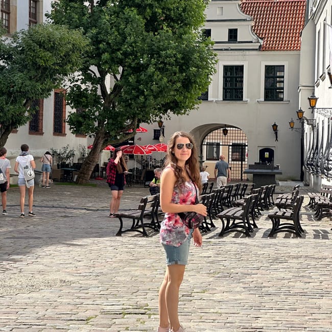 Dziedziniec w szczecinie z brukowaną nawierzchnią, ławkami i historycznymi budynkami.