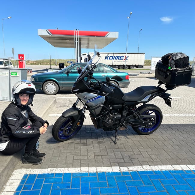 Motocyklistka siedzi przy zaparkowanym motocyklu yamaha tracer na stacji paliw w szczecinie.