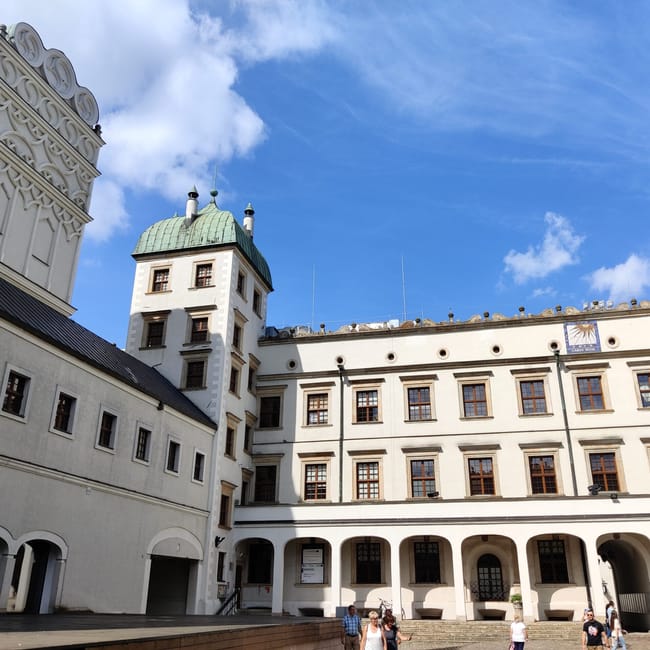Dziedziniec zamku książąt pomorskich w szczecinie z białymi fasadami i zielonym dachem wieży