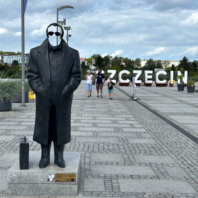 Pomnik krzysztofa jarzyny w szczecinie na promenadzie z napisem szczecin w tle