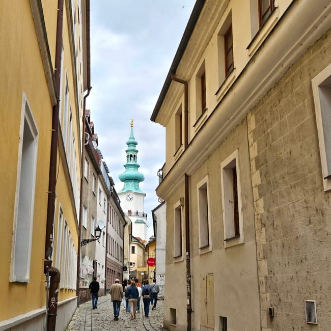 Bratysławska starówka z brukowaną uliczką i wieżą kościoła w tle