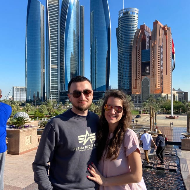 Para w abu dhabi przed emirates palace i nowoczesnymi wieżowcami.