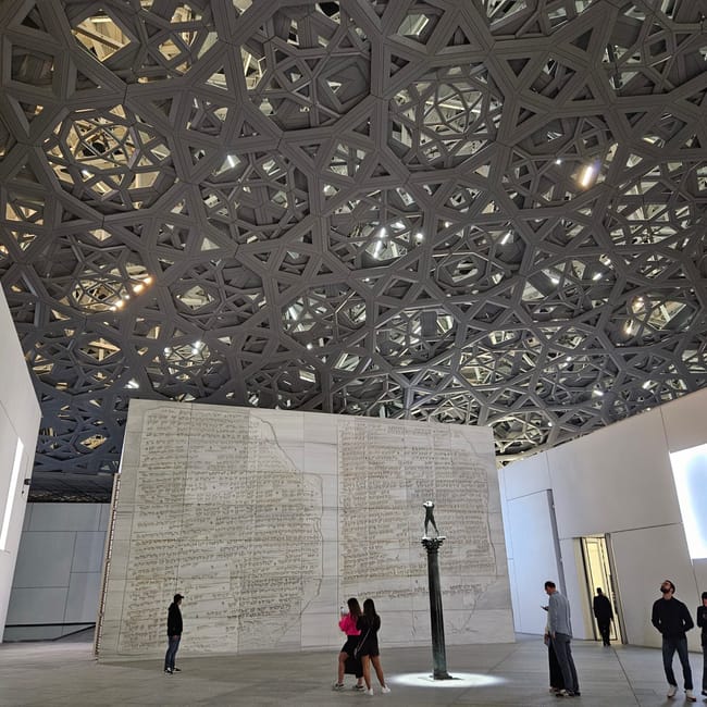 Luvre abu dhabi z ażurową kopułą i monumentalną instalacją w sali muzeum