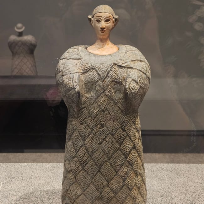 Rzeźba w louvre abu dhabi w abu zabi, przedstawiająca stylizowaną postać w geometrycznej szacie.