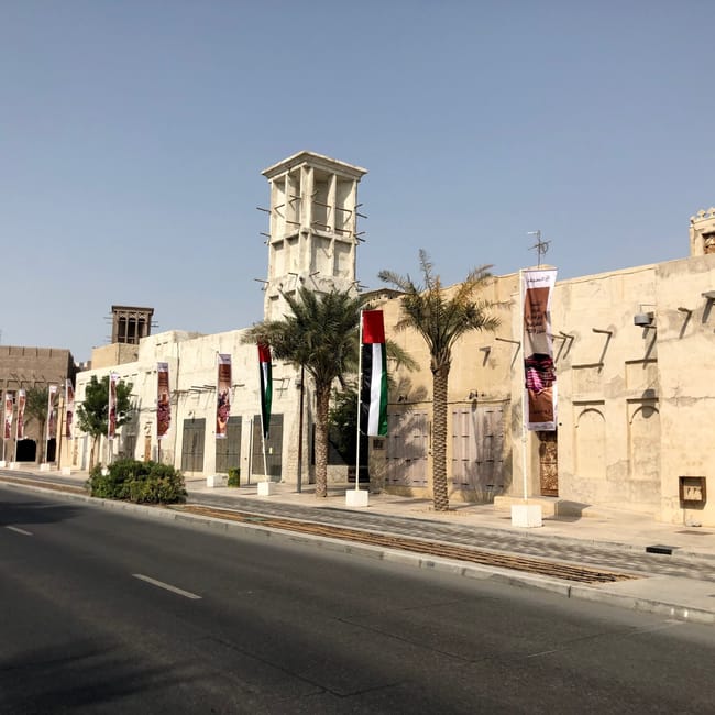Tradycyjne zabudowania w dubaju z wieżą wiatrową i flagami przy ulicy