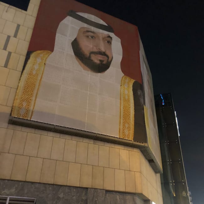 Nocny widok w dubaju z wielkim muralem portretowym na fasadzie budynku.
