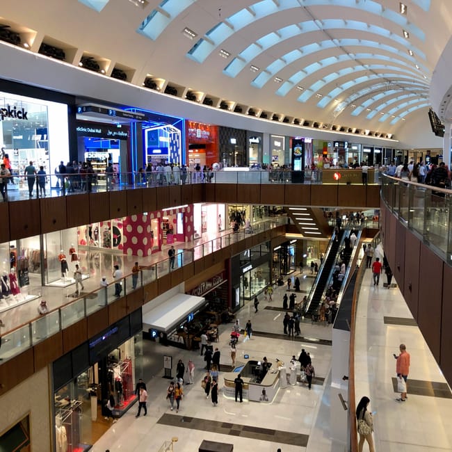 Wnętrze centrum handlowego w dubaju z kilkoma poziomami sklepów i ruchomymi schodami.
