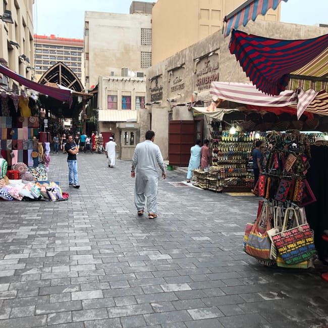 Targ na suku w dubaju z kolorowymi straganami i przechodniami.