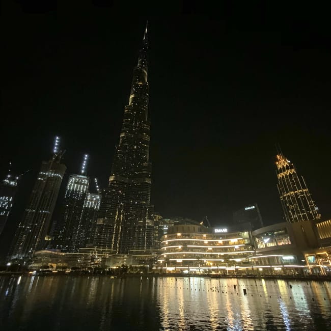 Wieżowiec burdż chalifa nocą w dubaju z odbiciami świateł w wodzie