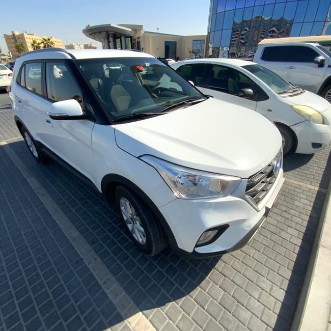 Białe samochody wypożyczone w dubai rental car, zaparkowane na placu w dubaju.