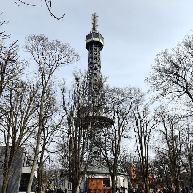 Wieża petrin w pradze, widoczna między bezlistnymi drzewami.