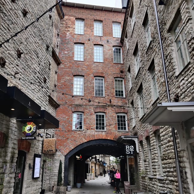 Tallinn alley between weathered stone buildings with brick facade and archway, estonia