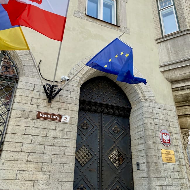 Tallinn, estonia—flags of poland, lithuania, and the eu in front of a historic arched door labeled vana turg 2