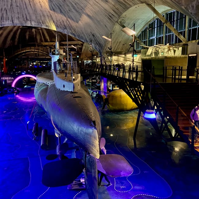 White submarine displayed indoors at the tallinn article photo in estonia, lit by colorful blue and purple lights