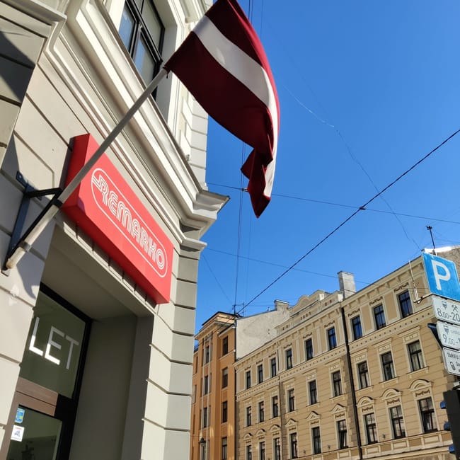 Rydzeńska ulica z flagą łotwy i szyldem remarko na fasadzie budynku