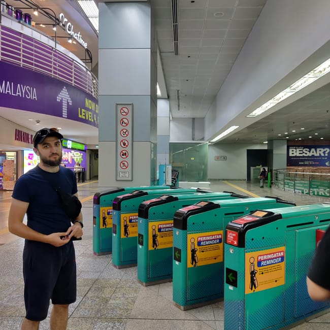 Bramki biletowe w kuala lumpur z mężczyzną w hali stacji.
