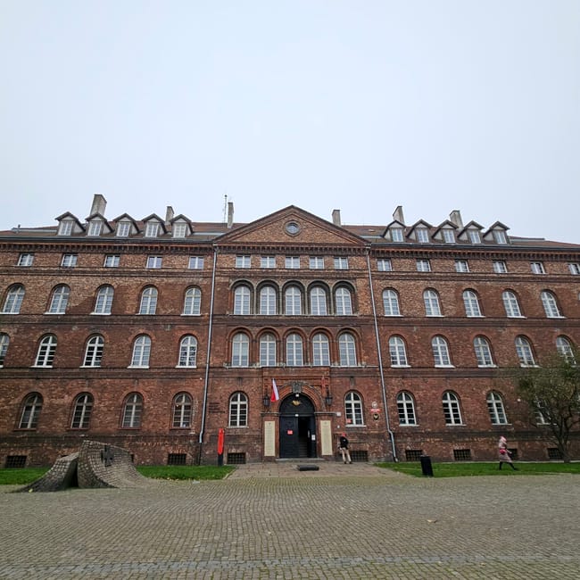 Muzeum poczty polskiej w gdańsku, ceglany budynek z wejściem i polską flagą.