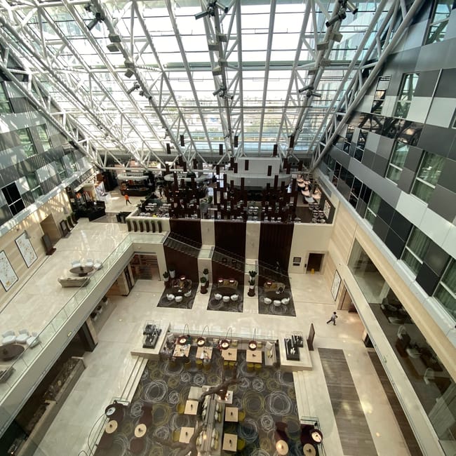 Atrium hotelu hyatt w dosze z przeszklonym dachem i strefą wypoczynkową.