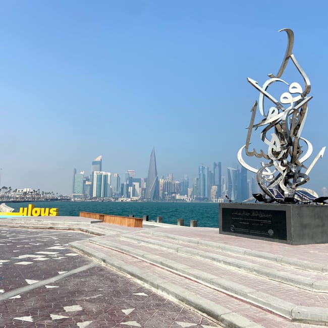 Nadmorska promenada w doha z metalową rzeźbą i panoramą wieżowców w tle