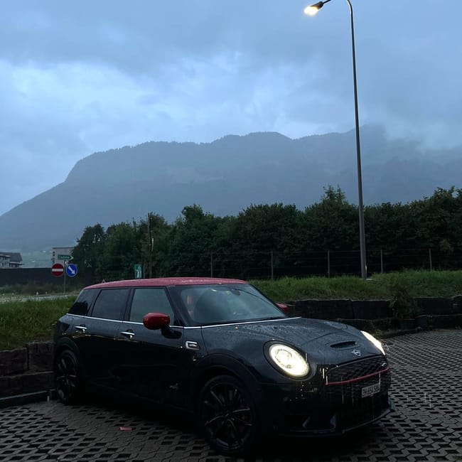 Samochód mini w interlaken w szwajcarii, zaparkowany przy drodze w deszczu o zmierzchu.