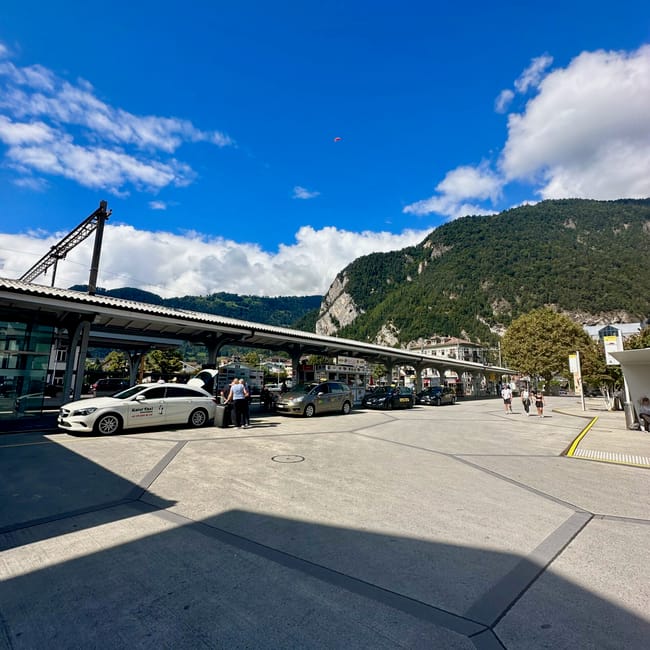 Dworzec w interlaken z peronami, taksówkami i górami w tle pod błękitnym niebem